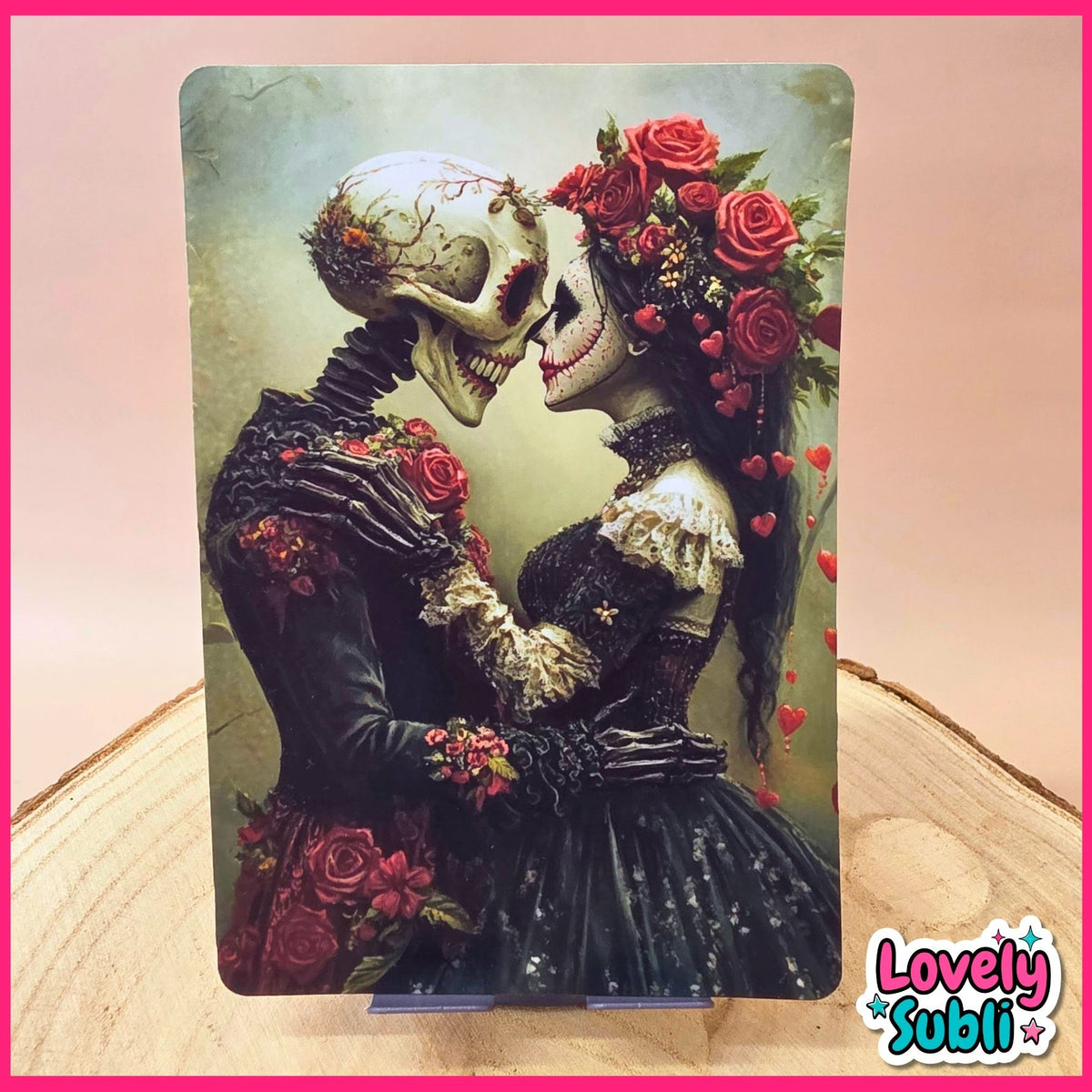 A vertical art print featuring a Day of the Dead style couple with a skeleton and a woman with red roses in a black dress, displayed on a wooden surface with a pink border and a 'Lovely Subli' logo in the corner.