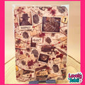 A rectangular wall art print or poster featuring a collage of western-crime-themed elements, including a silhouette in a hat labeled 'SUSPECT', a running man silhouette, fingerprints, blood splatters, small photo frames, and a revolver. The print is photographed hanging against a beige wall with a pink border around the image.