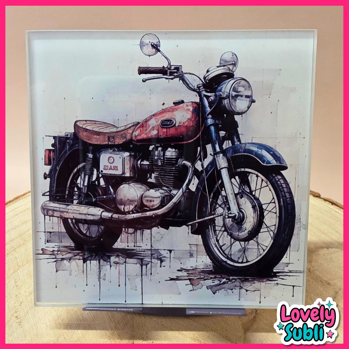 A square framed art print featuring a stylized watercolor-style illustration of a vintage motorcycle, displayed on a stand against a beige background with a pink border.