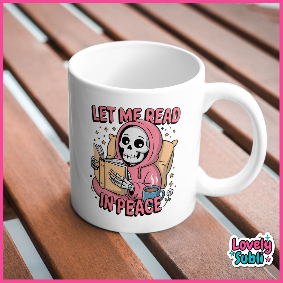 A white ceramic mug with a cartoon grim reaper reading in a pink hoodie and the text 'LET ME READ IN PEACE' on the side, placed on a brown wooden slatted surface.