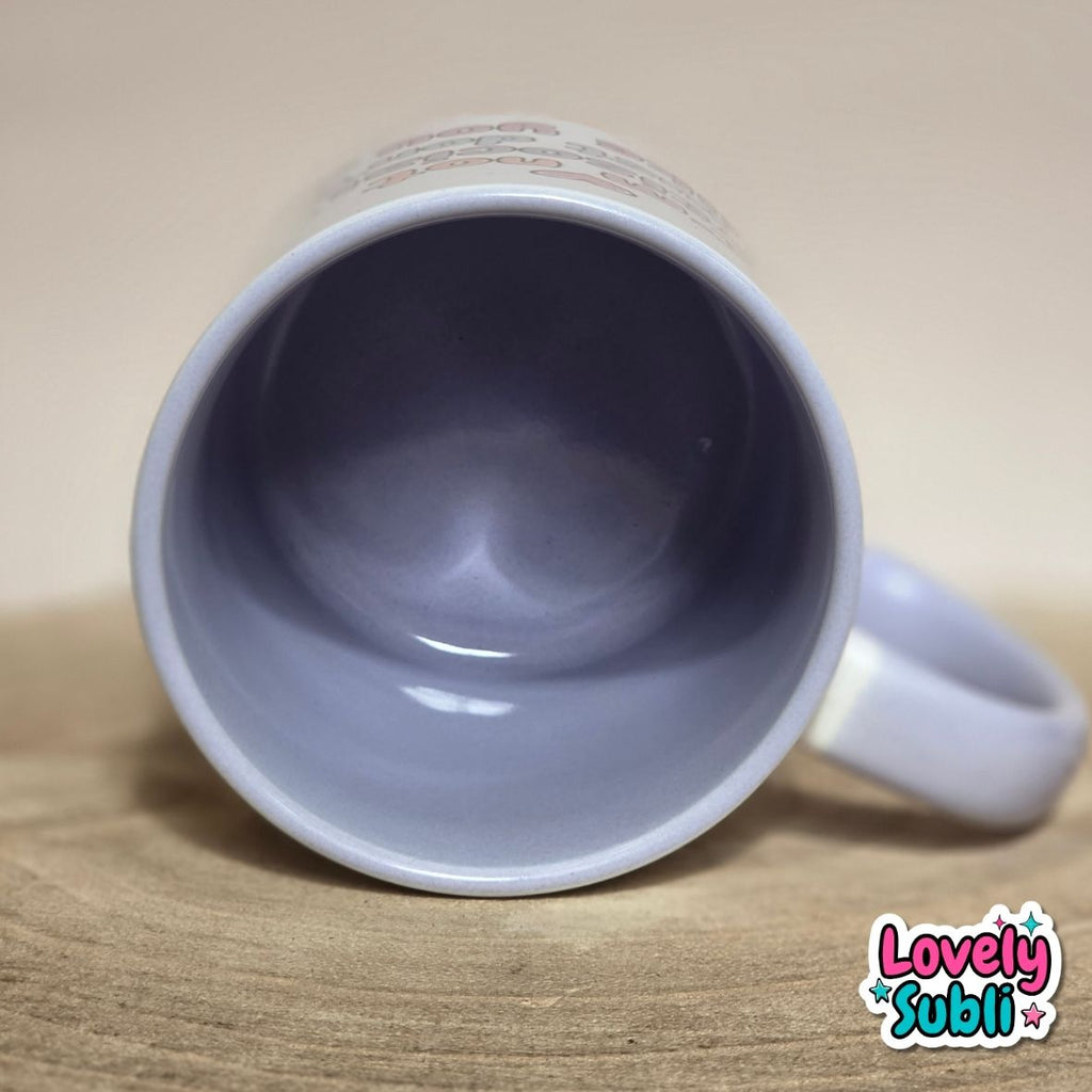 A lilac ceramic mug shown from a top-down angle, lying on its side on a wooden surface with a beige background. The inside of the mug is a dusty lavender-blue, and the handle is on the right.