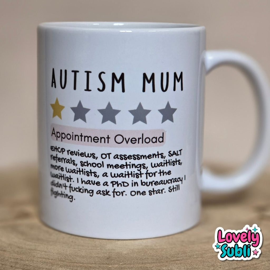 A white ceramic mug printed with the text 'AUTISM MUM' and 'Appointment Overload' with a humorous list of work-related burdens, plus one gold star out of five gray stars. The mug is photographed on a wooden surface against a neutral beige background.