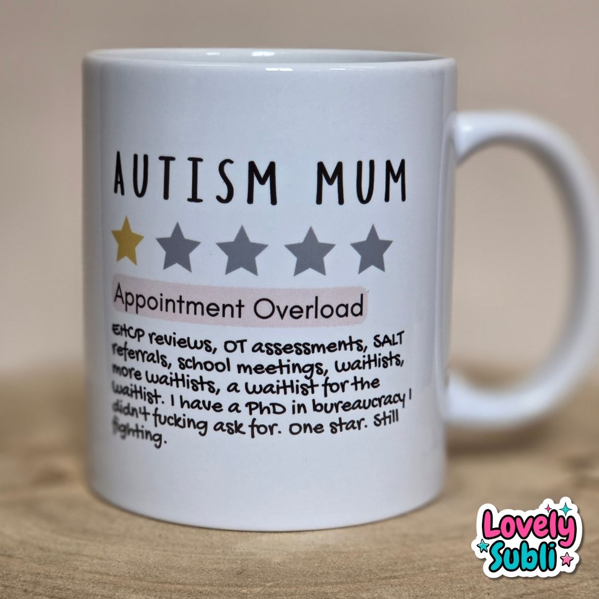 A white ceramic mug printed with the text 'AUTISM MUM' and 'Appointment Overload' with a humorous list of work-related burdens, plus one gold star out of five gray stars. The mug is photographed on a wooden surface against a neutral beige background.