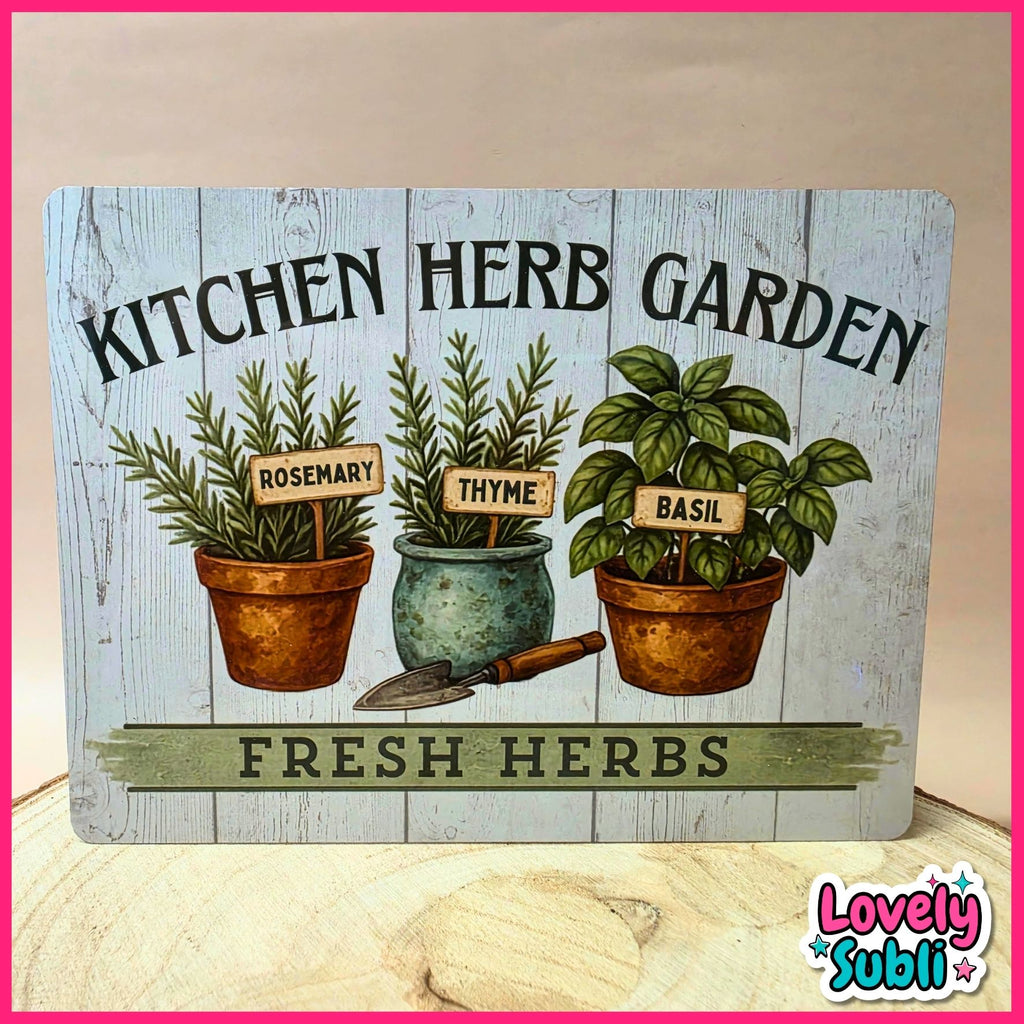 A decorative rectangular sign reading 'KITCHEN HERB GARDEN' and 'FRESH HERBS,' featuring illustrated rosemary, thyme, and basil plants in pots with small gardening tools. The sign is photographed on a light wood surface against a beige wall, with a pink border around the image and a 'Lovely Subli' logo in the lower right corner.