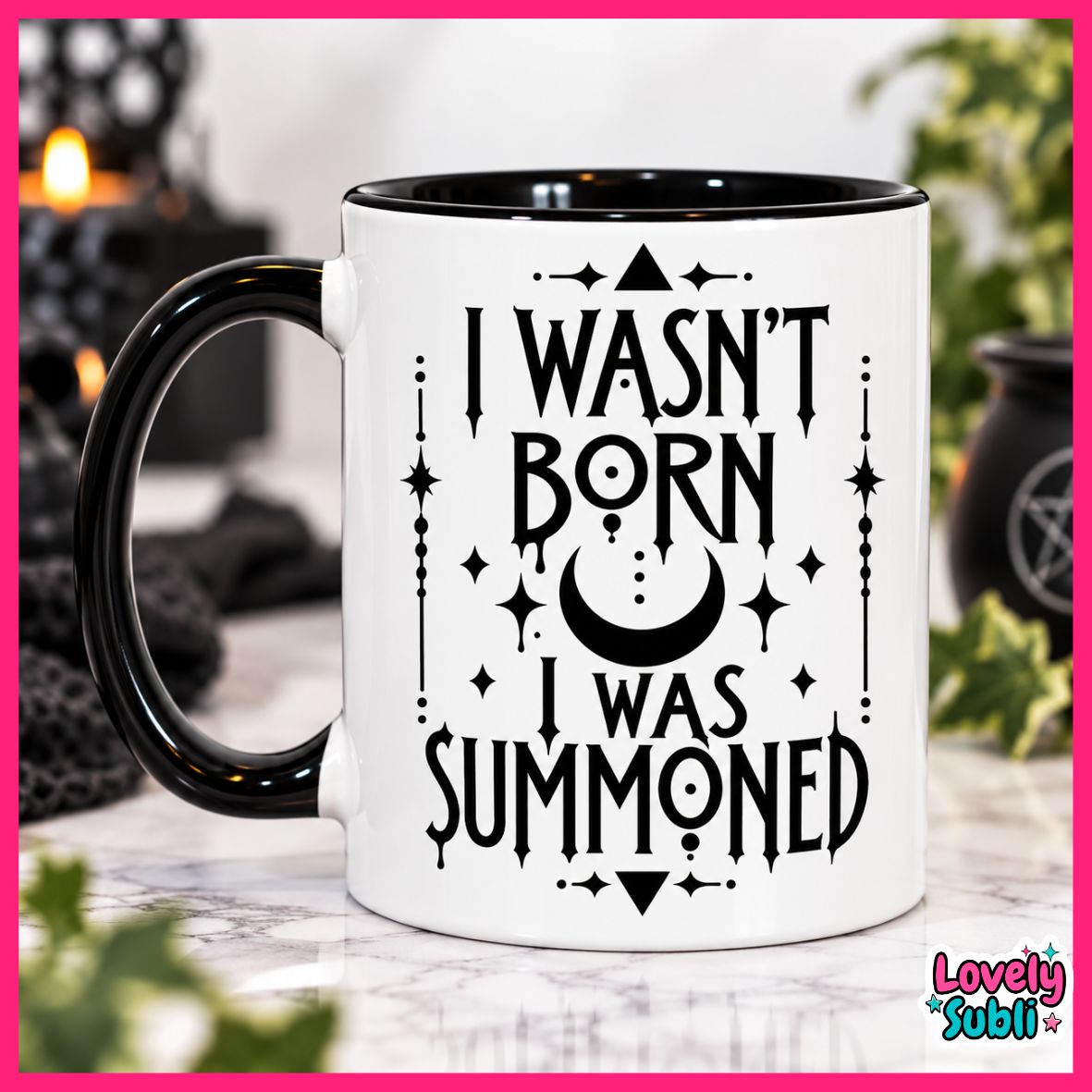 A white ceramic mug with a black handle and black interior, printed with the phrase 'I WASN'T BORN I WAS SUMMONED' in black gothic-style lettering with a crescent moon and star accents. The mug is shown on a marble-like surface with a blurred mystical background and a pink border around the image.