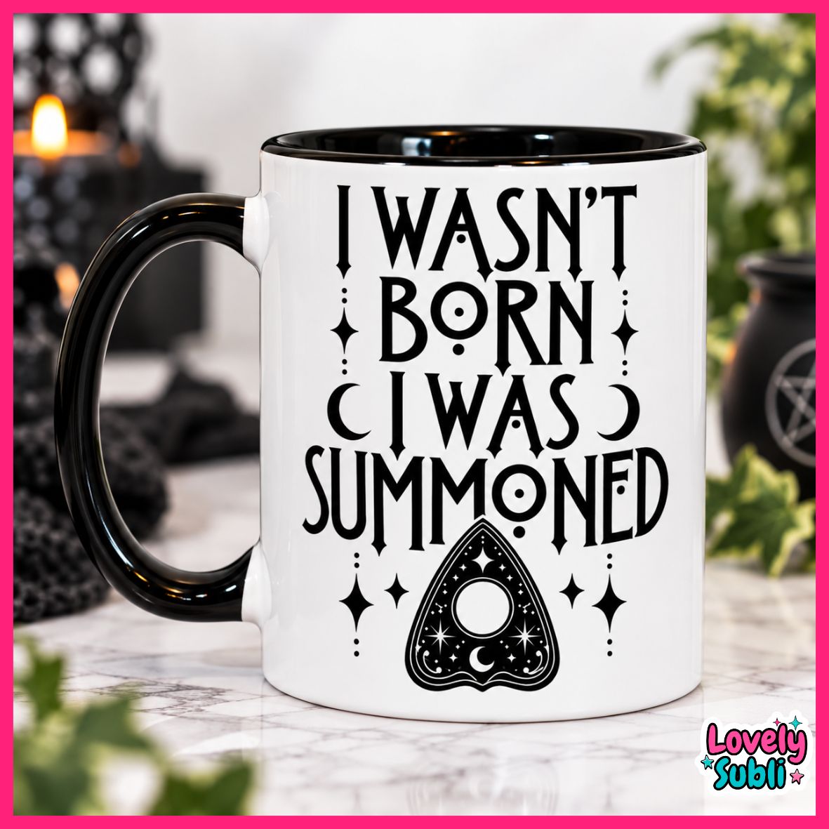 A white ceramic mug with a black handle and black interior, printed with the phrase 'I WASN'T BORN I WAS SUMMONED' in black lettering above a black triangular occult-style symbol. The mug is photographed on a marble-like surface with blurred black candles and greenery in the background.