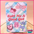 A square decorative sign or plaque with rounded corners featuring a pastel plaid background and cute pink-themed illustrations, including a band-aid with hearts, a pink gift box, a heart-shaped candy labeled 'SMUT', 'Call Me A Good Girl' in large pink text, and a drink cup labeled 'Plot Fuel'. The sign is displayed on a small stand on a wooden surface with a pink backdrop.