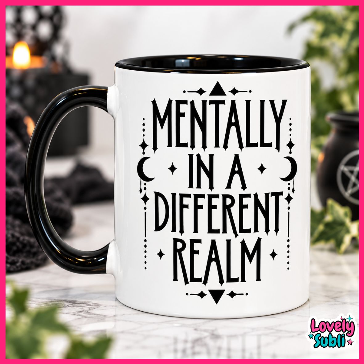 A white ceramic mug with a black handle and black interior, printed with the phrase 'MENTALLY IN A DIFFERENT REALM' in black lettering with celestial and geometric motifs. The mug is shown on a marble surface with a blurred cozy background featuring candles and plants.
