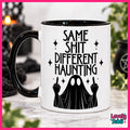 A white ceramic mug with a black handle and black interior, printed with the phrase 'SAME SHIT DIFFERENT HAUNTING' above a black ghost figure making middle fingers. The mug is photographed on a marble-like surface with a blurred Halloween-themed background, framed by a bright pink border with a 'Lovely Subli' logo in the lower right.