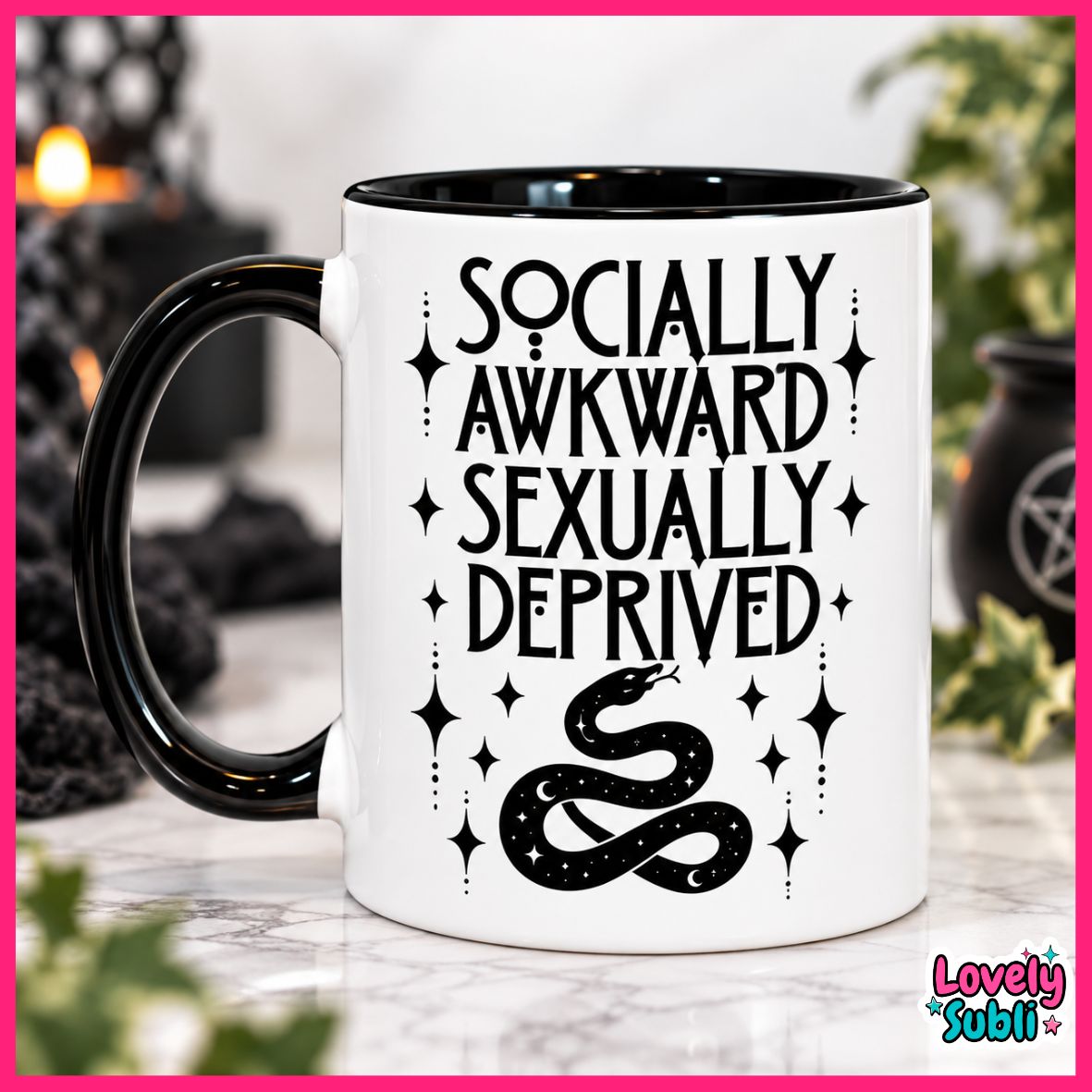 A white ceramic mug with a black handle and black interior, printed with the phrase 'SOCIALLY AWKWARD SEXUALLY DEPRIVED' in black lettering above a black snake illustration with stars. The mug is photographed on a marble-like surface with a softly blurred indoor background and a pink border around the image.